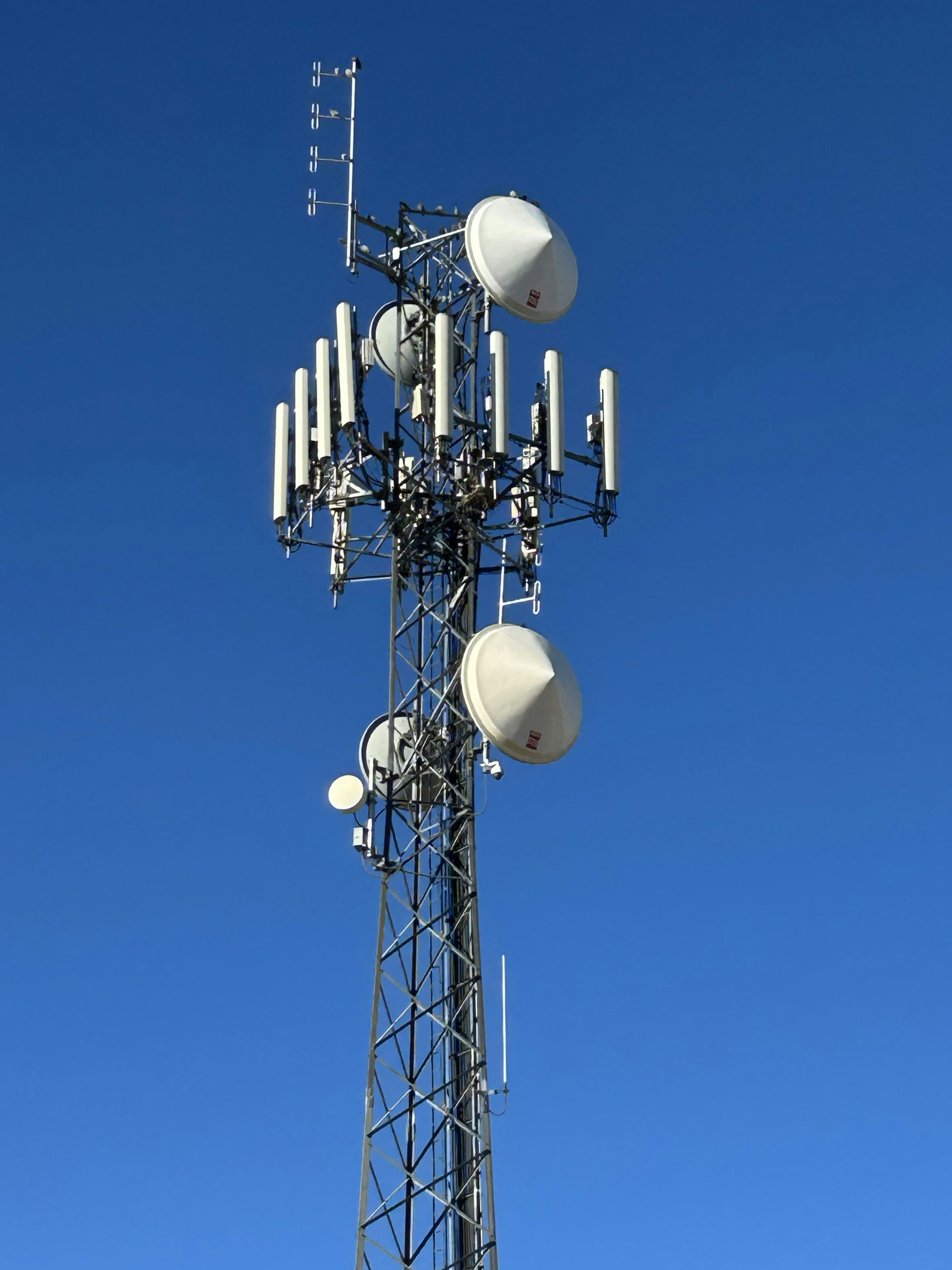 Telecommunication tower with antenna equipment against a blue sky